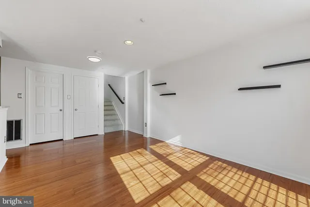 a view of an empty room with wooden floor and stairs