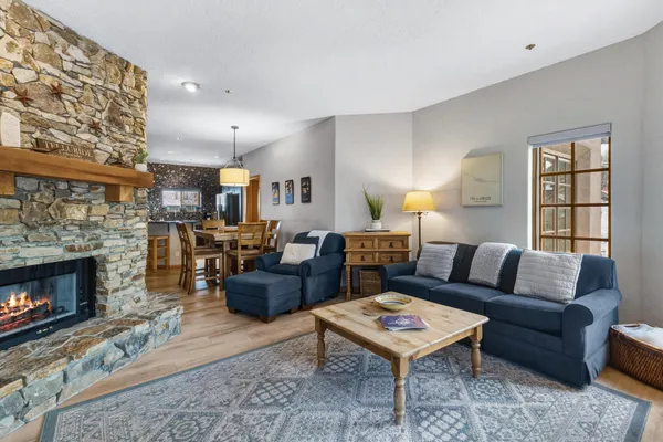 a living room with furniture a rug a fireplace and a window