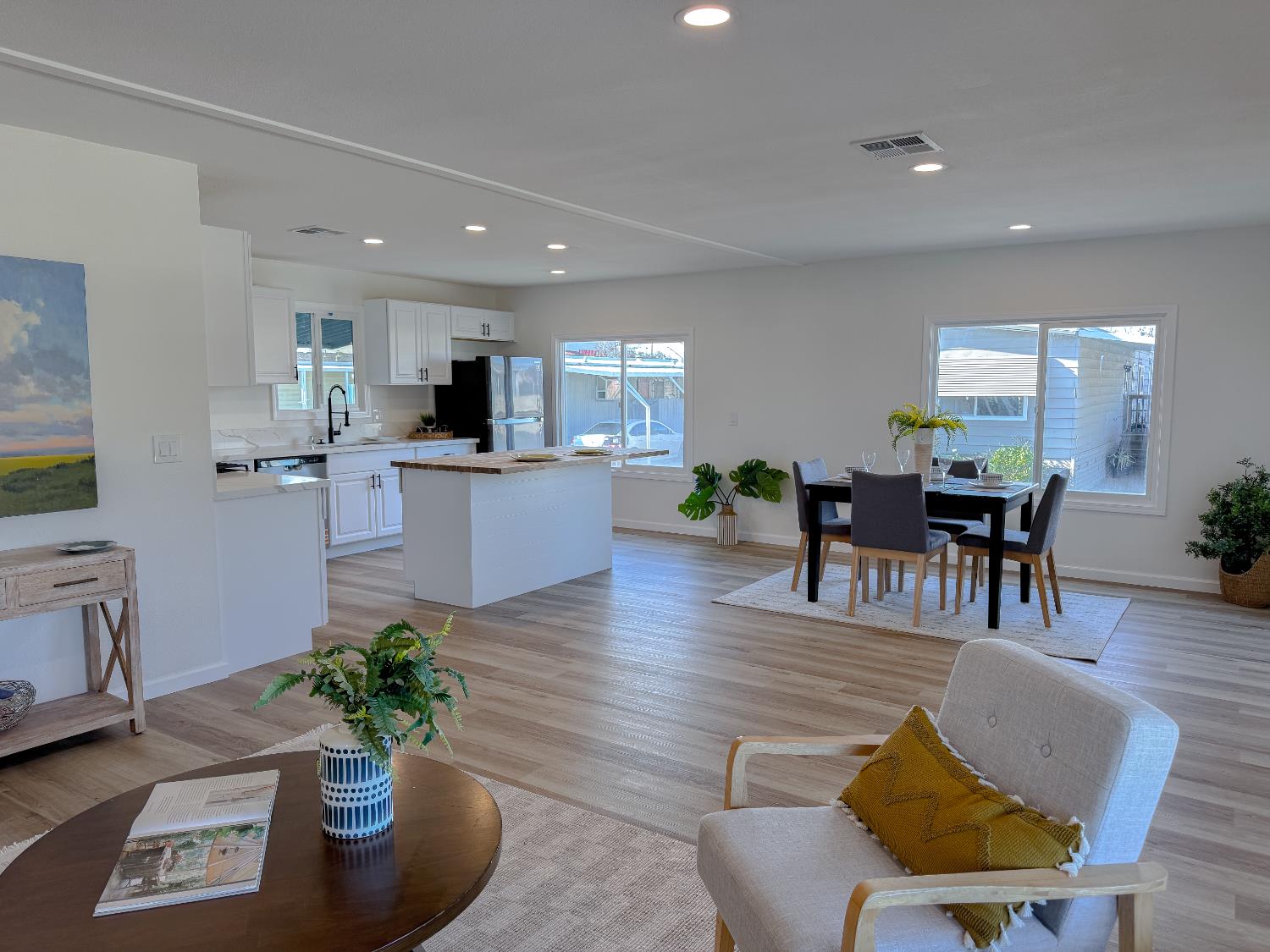 a living room with furniture kitchen view and a wooden floor