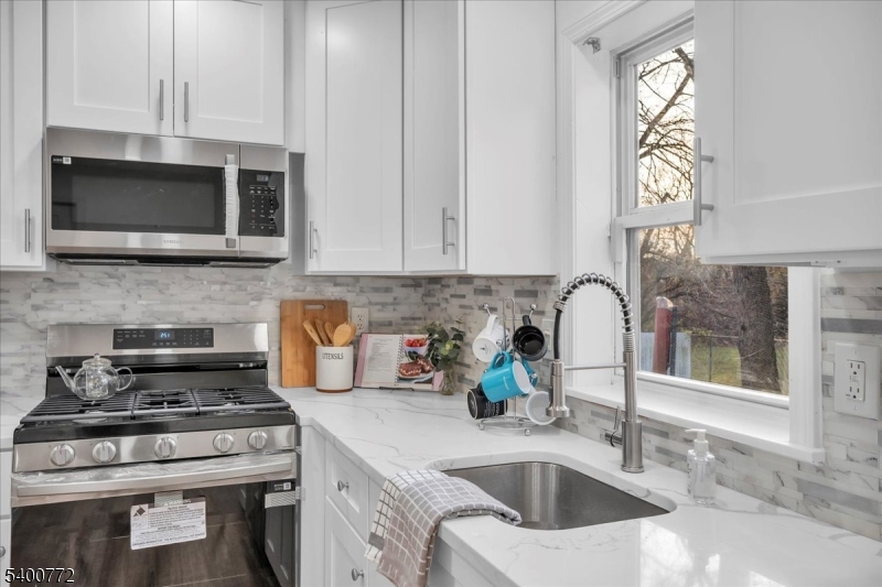 348 Silk Street Lawnside, NJ 08045 - Photo 8 of 24 a kitchen with stainless steel appliances granite countertop a sink a stove and a microwave