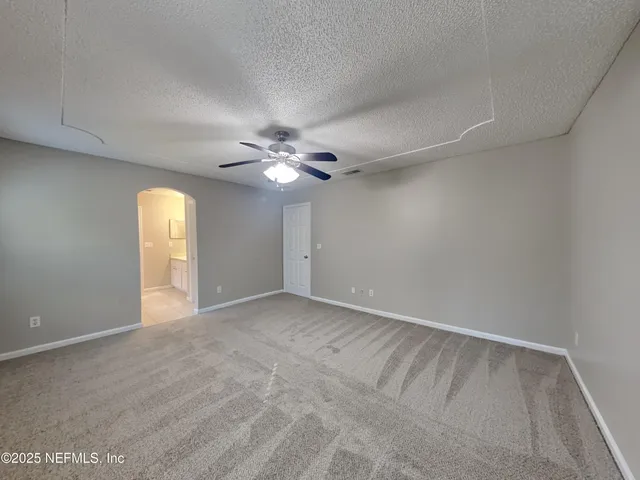 a view of an empty room with a chandelier fan