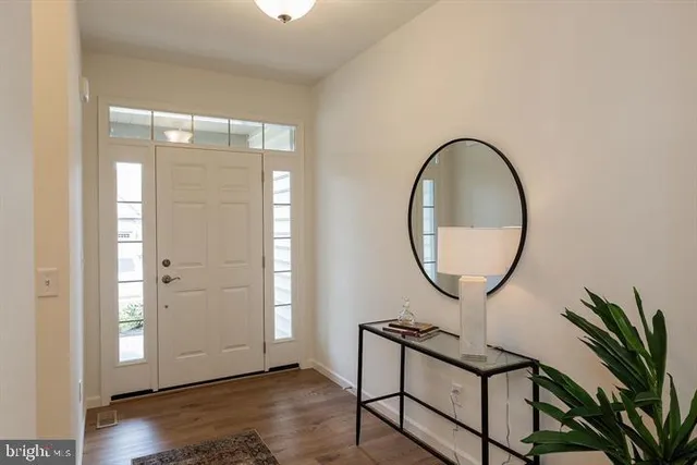 an entryway with wooden floor and mirror