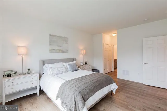 a spacious bedroom with a bed and a lamp