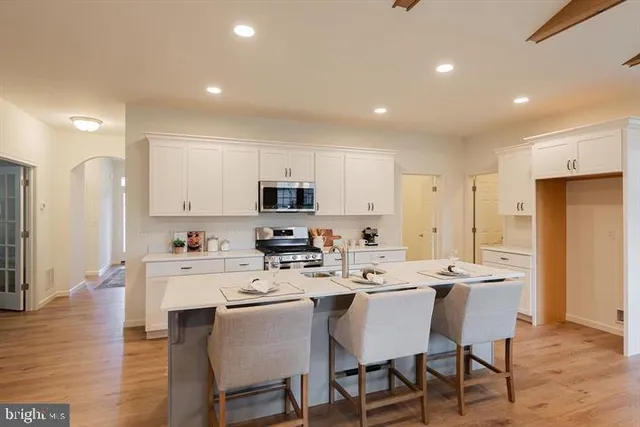 a kitchen with stainless steel appliances a dining table chairs refrigerator and sink