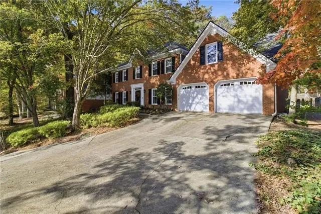 a front view of a house with a yard and large trees
