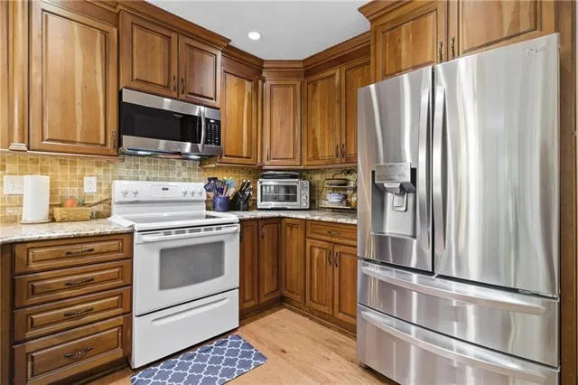 a kitchen with stainless steel appliances granite countertop a refrigerator sink and stove