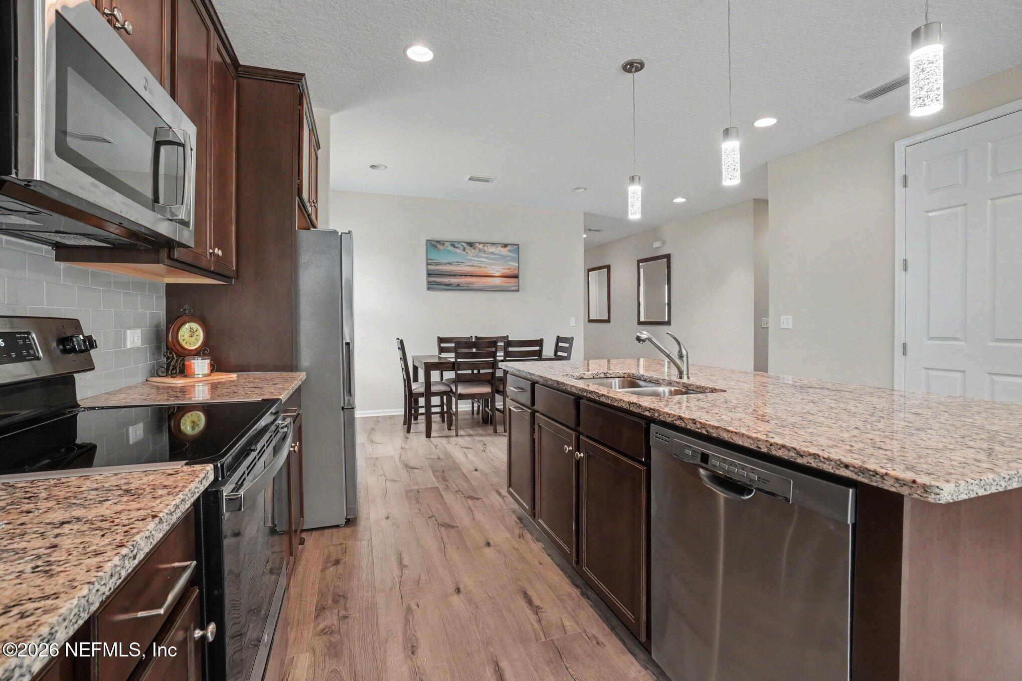 4630 Pine Ridge Parkway Middleburg, FL 32068 - Photo 11 of 35 a kitchen with stainless steel appliances granite countertop wooden cabinets a stove top oven a sink and dishwasher