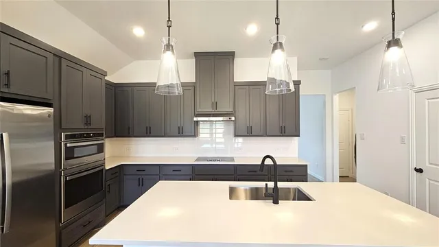a kitchen with stainless steel appliances kitchen island granite countertop a refrigerator and a sink