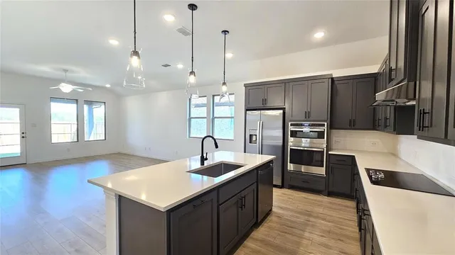 a kitchen with stainless steel appliances kitchen island granite countertop a sink a microwave and wooden floor