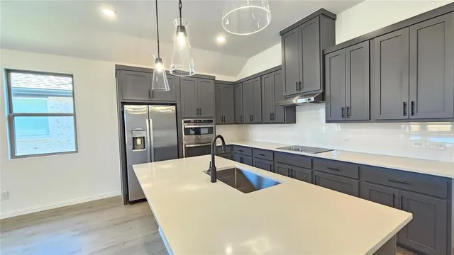 a kitchen with stainless steel appliances granite countertop a sink a stove and a refrigerator