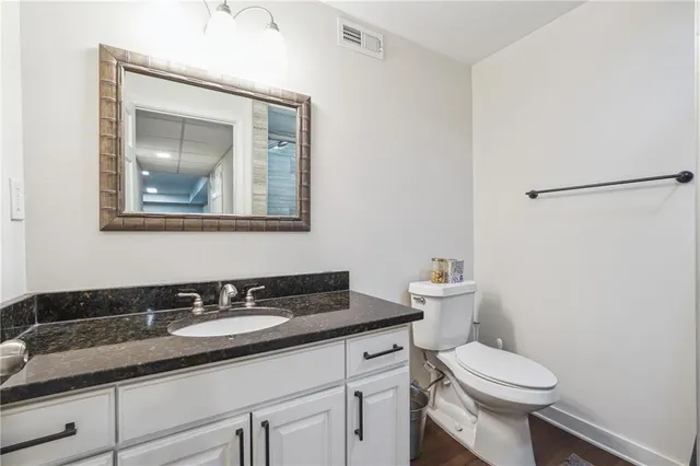 a bathroom with a granite countertop toilet sink and mirror