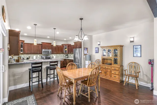 a dining area with stainless steel appliances kitchen island granite countertop a dining table chairs and a oven