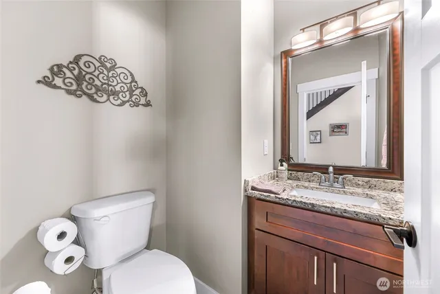 a bathroom with a granite countertop toilet sink and mirror
