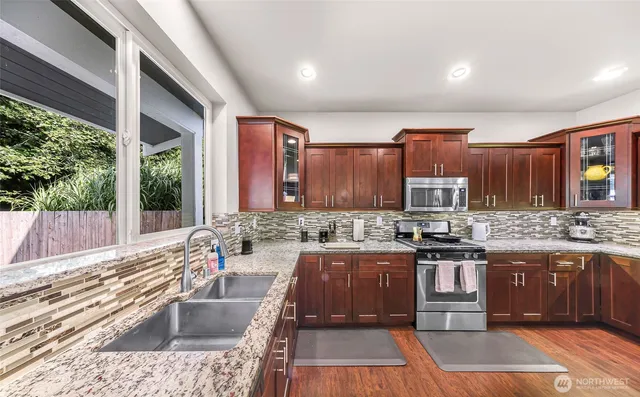 a kitchen with stainless steel appliances granite countertop a sink stove and cabinets