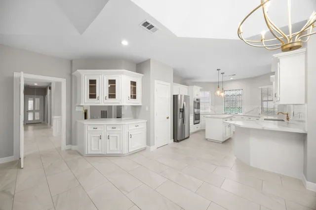 a large white kitchen with kitchen island a sink stainless steel appliances and cabinets