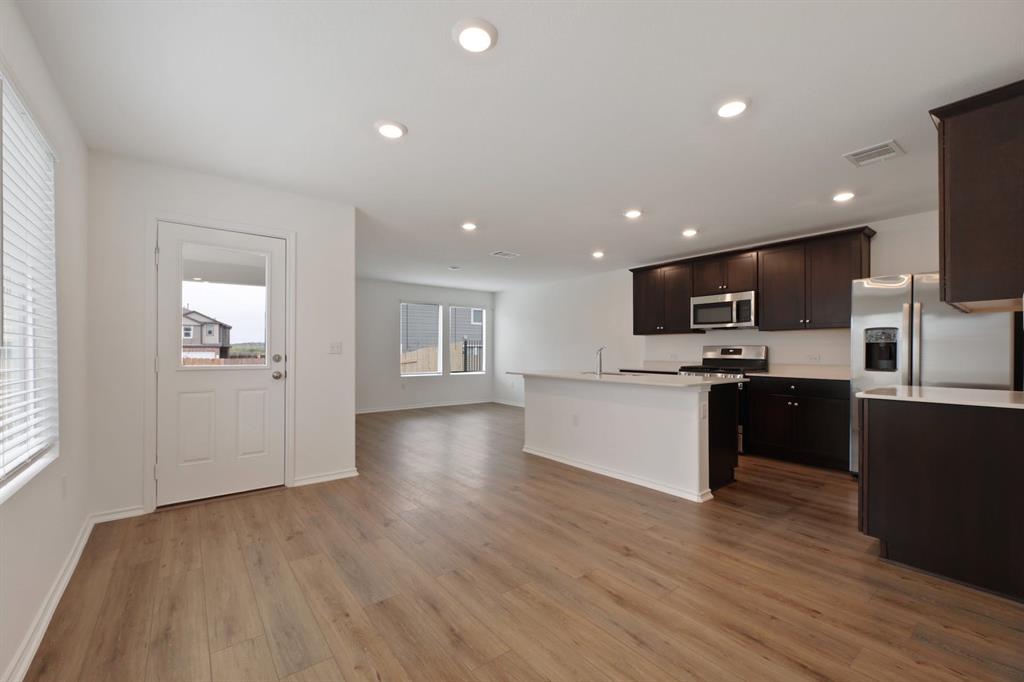 12213 Rising Moon Lane Del Valle, TX 78617 - Photo 11 of 11 a large kitchen with cabinets wooden floor and stainless steel appliances