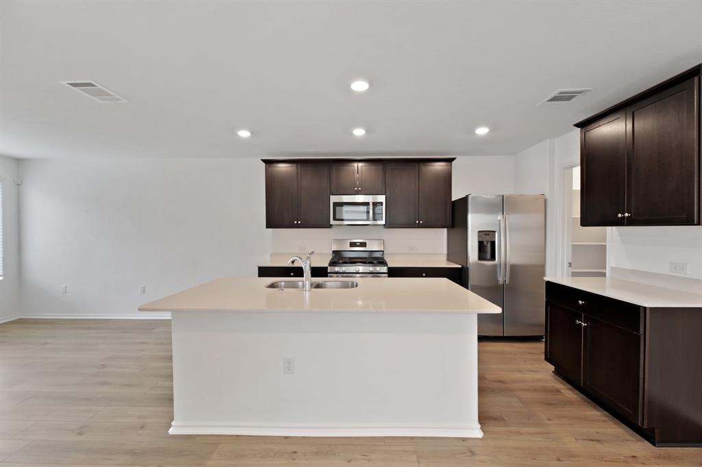12213 Rising Moon Lane Del Valle, TX 78617 - Photo 3 of 11 a kitchen with stainless steel appliances a refrigerator sink and microwave
