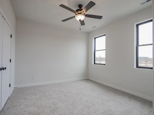 an empty room with windows and fan