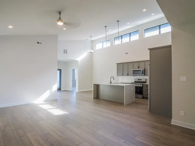 a large kitchen with a large counter top a sink stainless steel appliances and cabinets