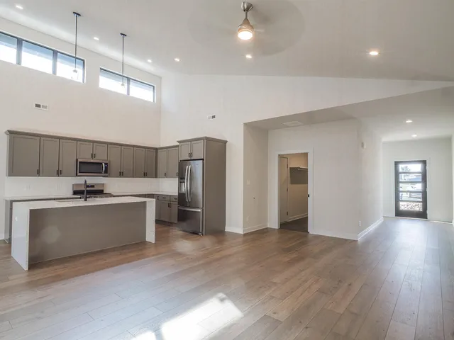 a large white kitchen with lots of counter space a sink stainless steel appliances and cabinets