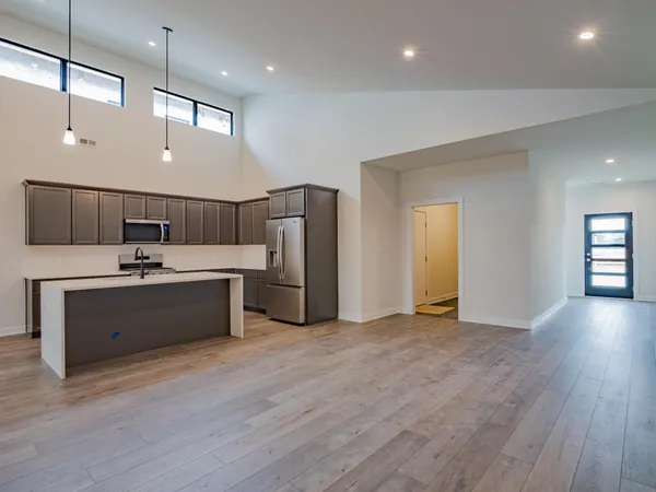 a kitchen with stainless steel appliances a sink a stove a refrigerator a center island and cabinets