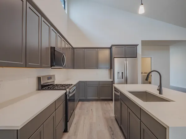 a kitchen with stainless steel appliances granite countertop a sink a stove and a wooden floors
