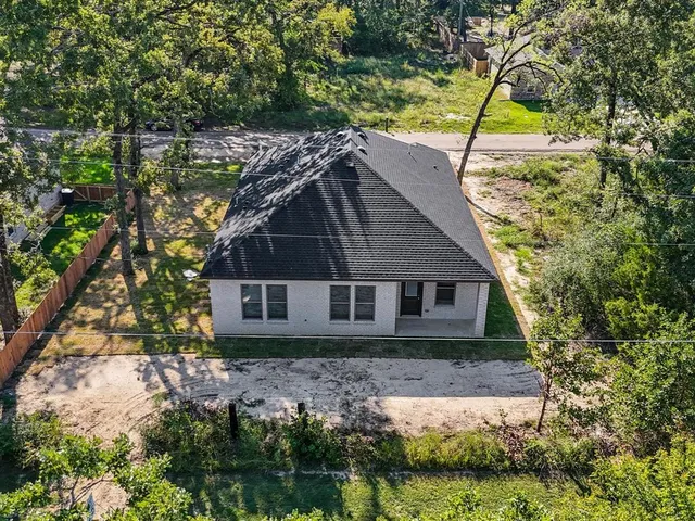 an aerial view of residential houses with outdoor space and trees