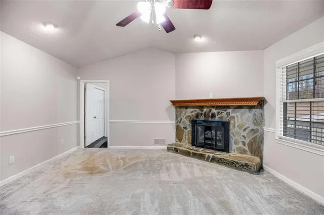 a view of an empty room with window and fireplace