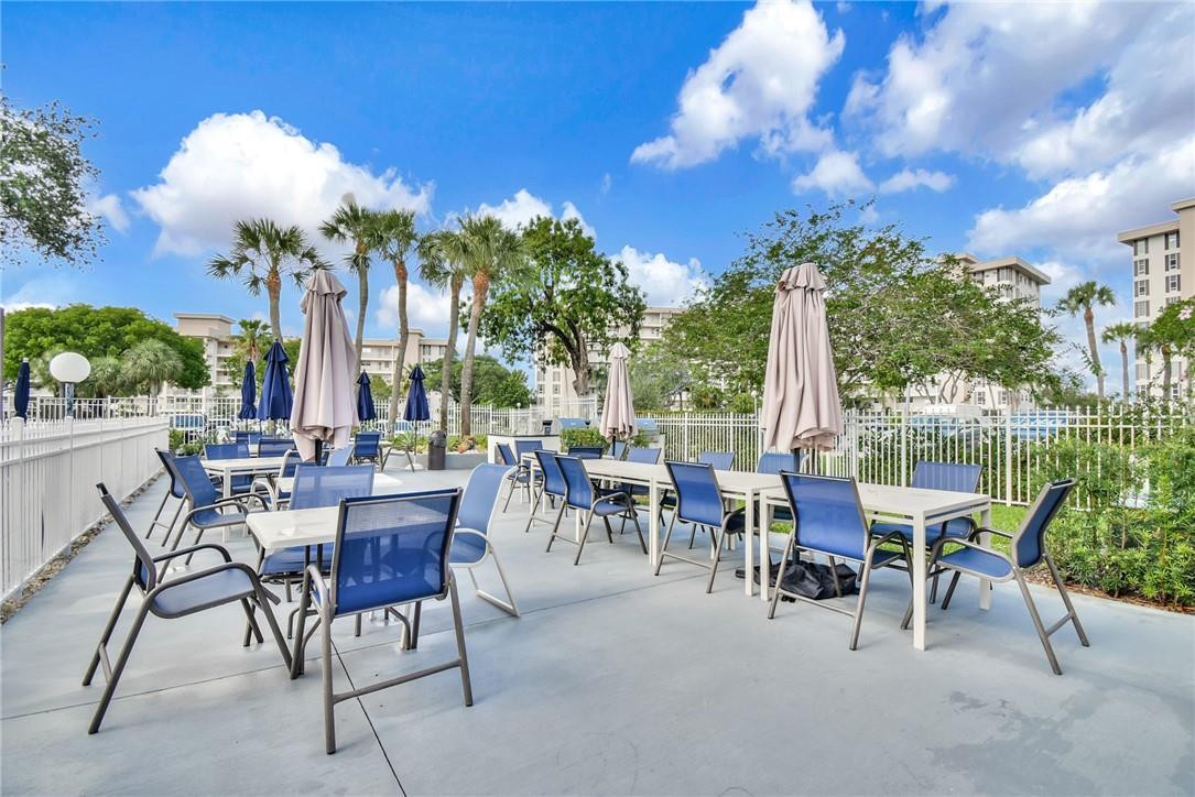2601 South Course Drive, Unit 409 Pompano Beach, FL 33069 - Photo 38 of 58 a view of a patio with a dining table and chairs with wooden floor