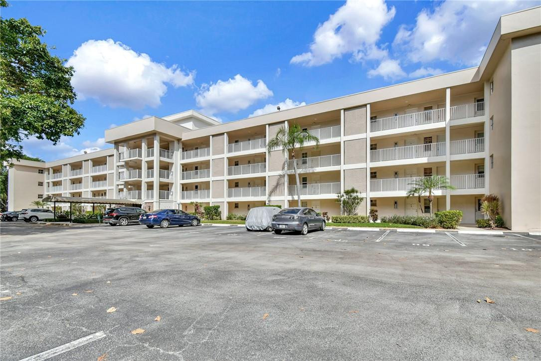 2601 South Course Drive, Unit 409 Pompano Beach, FL 33069 - Photo 42 of 58 a view of a building with lot of cars parked in front of it
