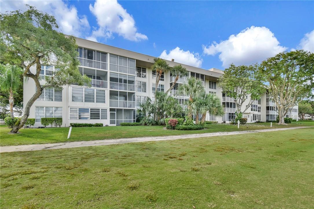 2601 South Course Drive, Unit 409 Pompano Beach, FL 33069 - Photo 48 of 58 a view of a big building with a big yard and large trees