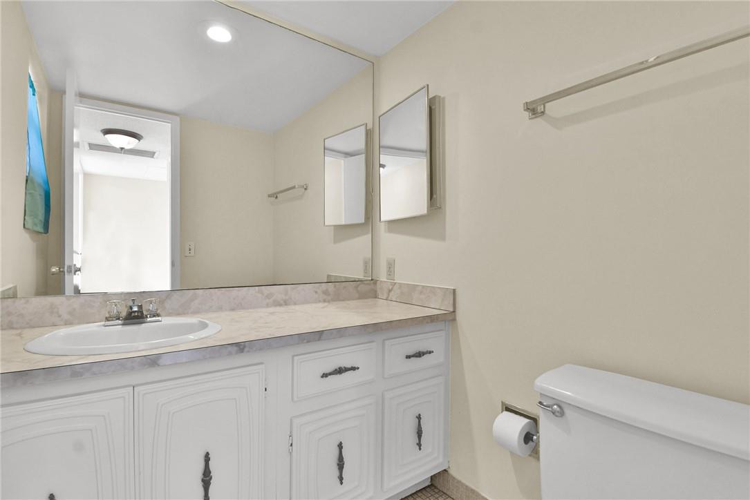 2601 South Course Drive, Unit 409 Pompano Beach, FL 33069 - Photo 9 of 58 a bathroom with a granite countertop sink a toilet and a mirror