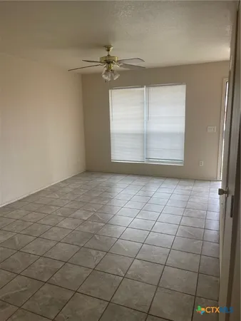an empty room with windows and fan