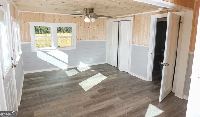 a view of empty room with wooden floor and fan