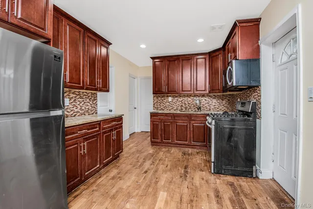 a kitchen with granite countertop wooden cabinets a stove top oven and stainless steel appliances