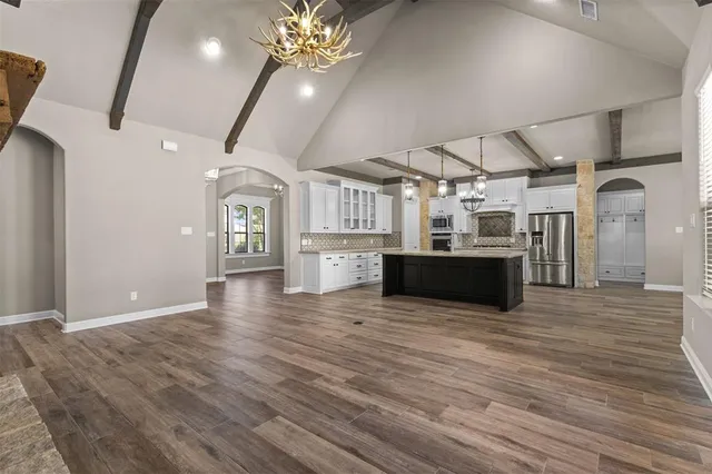a view of a big room with wooden floor and a kitchen