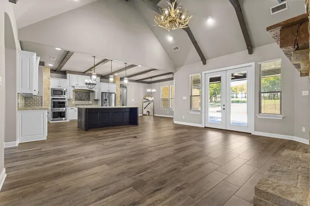 a view of a livingroom with furniture a kitchen view and wooden floor