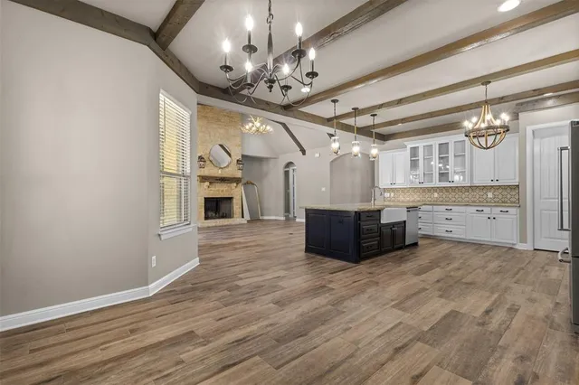 an empty room with wooden floor chandelier fan and windows