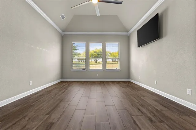 an empty room with wooden floor chandelier and windows