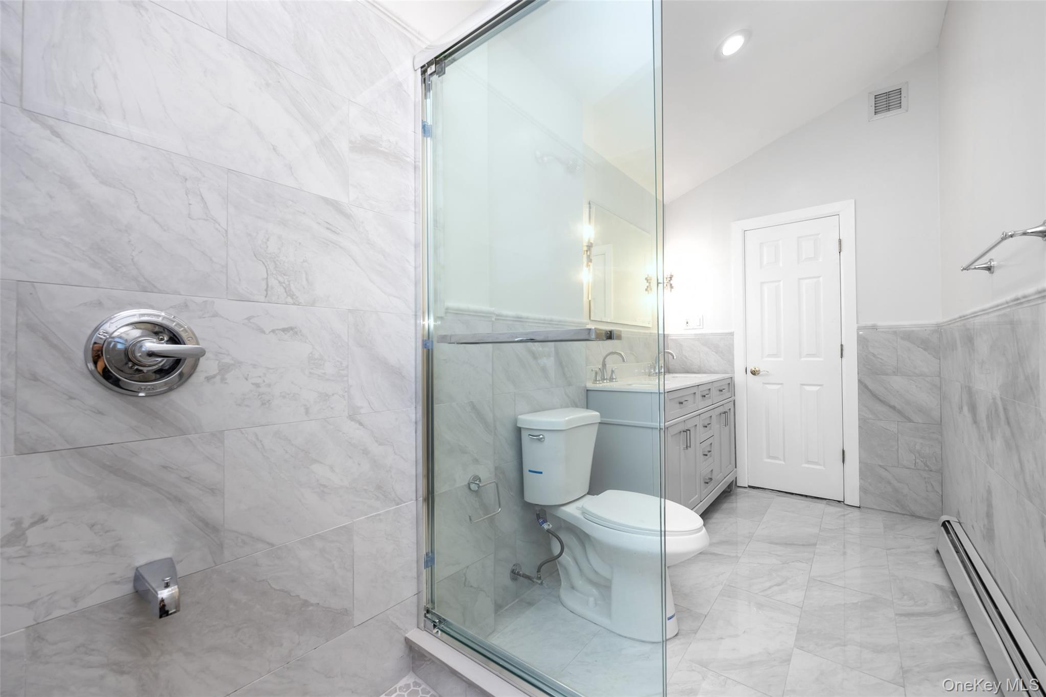36 Red Spring Lane Glen Cove, NY 11542 - Photo 15 of 33 Secondary Bathroom – Freshly updated with marble-look tile, a dual-sink vanity, and a glass-enclosed shower for a sleek, contemporary finish.