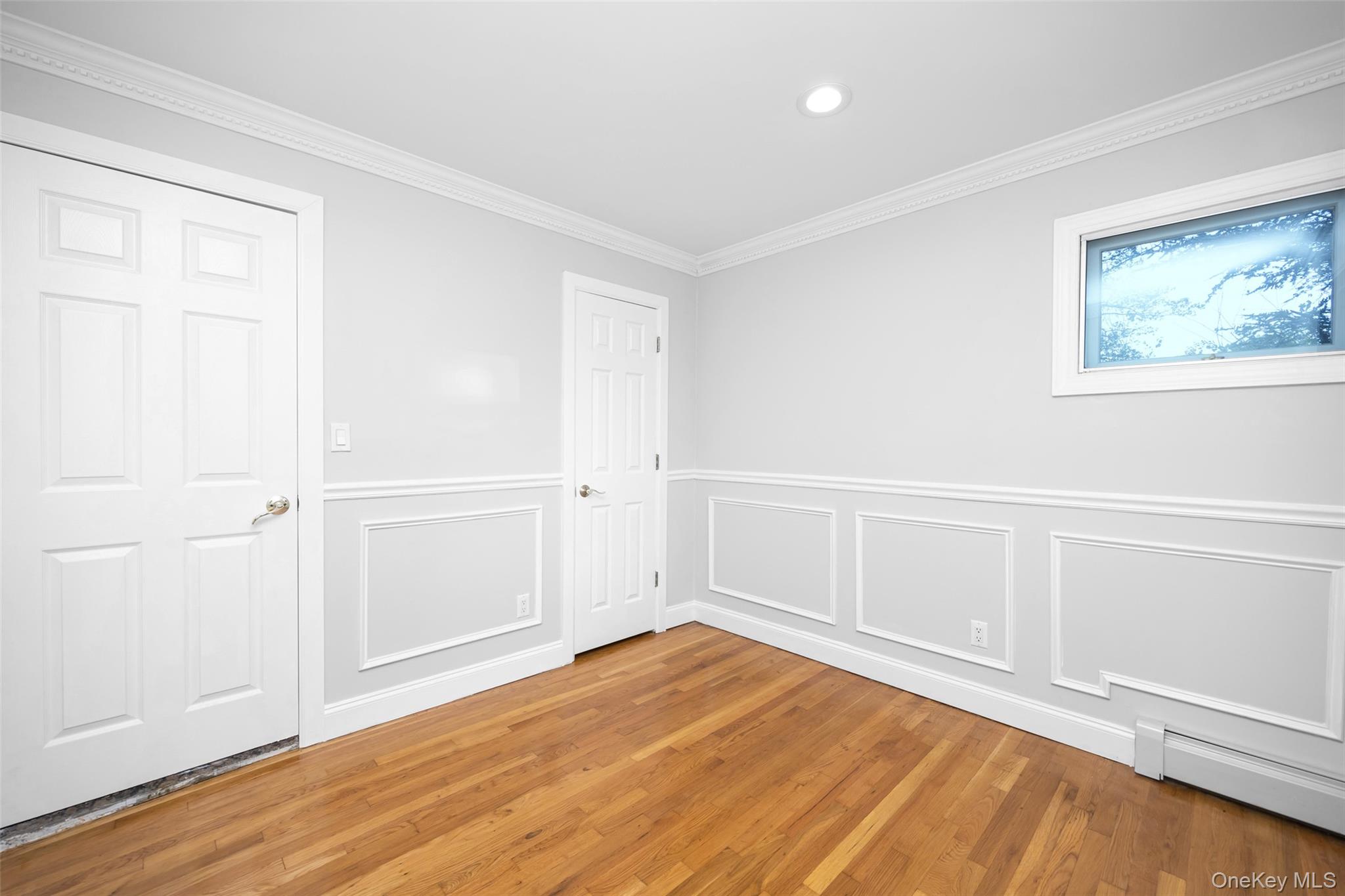 36 Red Spring Lane Glen Cove, NY 11542 - Photo 17 of 33 Secondary Bedroom – Sunlit room with distinctive clerestory windows, vaulted ceiling, and warm hardwood flooring—perfect for a stylish guest or secondary bedroom.