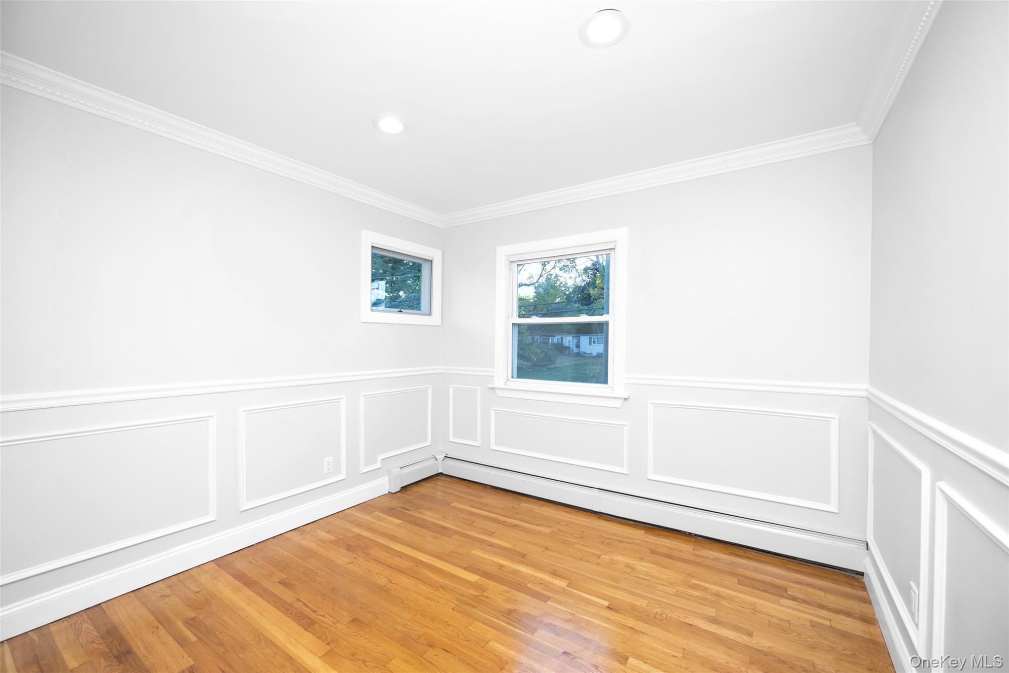36 Red Spring Lane Glen Cove, NY 11542 - Photo 21 of 33 Third Bedroom – Elegant and versatile space featuring decorative wall molding, crown trim, and abundant natural light through double windows.