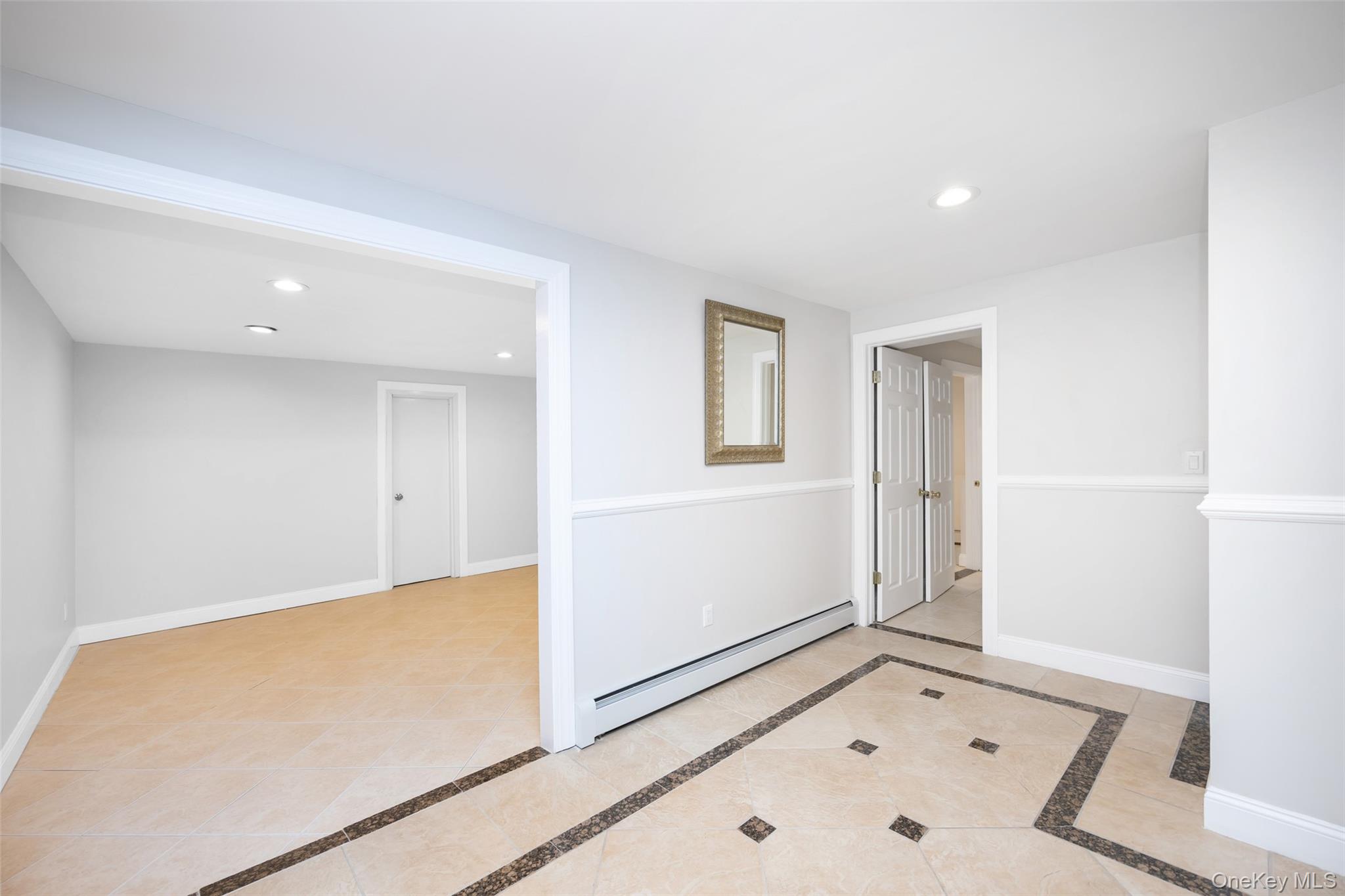 36 Red Spring Lane Glen Cove, NY 11542 - Photo 22 of 33 Lower-level overview – Open-concept space with seamless flow between the family room and main stairway, designed for comfort and functionality.