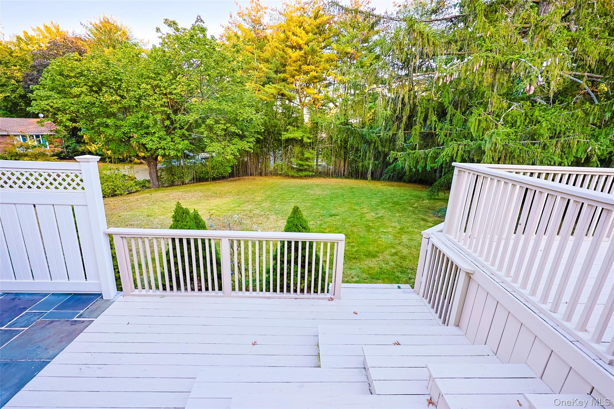 36 Red Spring Lane Glen Cove, NY 11542 - Photo 26 of 33 Upper Deck – Expansive deck off the main level with dual lantern lights and railing accents, offering peaceful tree-lined views and plenty of space for outdoor dining.