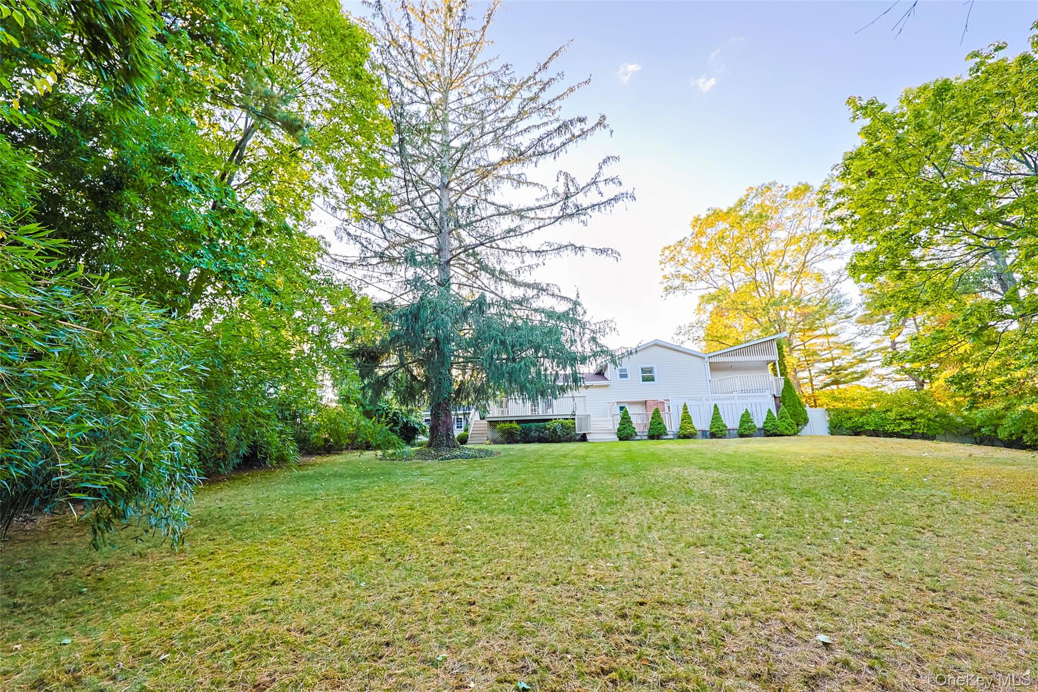 36 Red Spring Lane Glen Cove, NY 11542 - Photo 30 of 33 Backyard overview – Spacious, level yard surrounded by mature landscaping and greenery, providing plenty of room for outdoor activities.