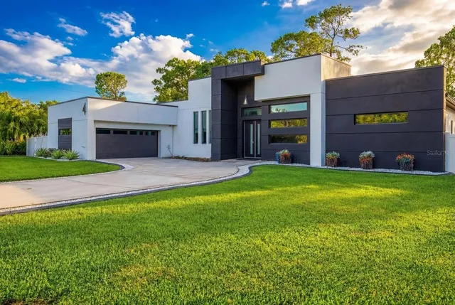 a view of a house with a small yard and a large tree