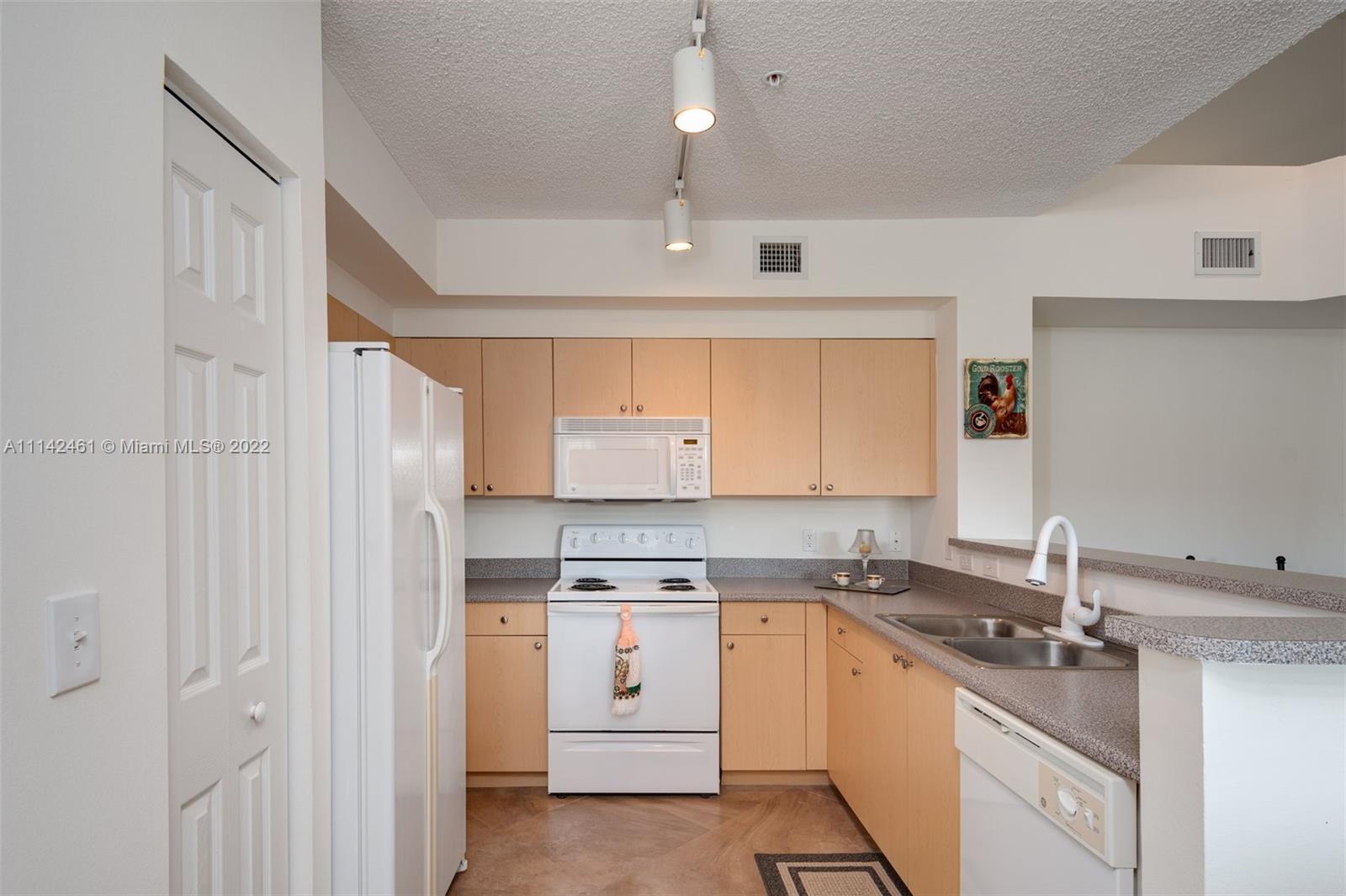 8030 North Nob Hill Road, Unit 306 Tamarac, FL 33321 - Photo 11 of 26 a kitchen with a sink dishwasher a stove and white cabinets