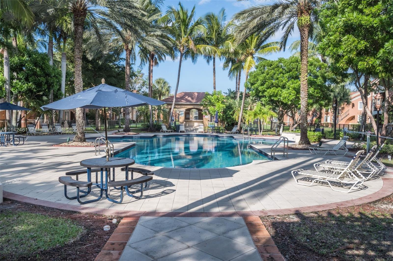 8030 North Nob Hill Road, Unit 306 Tamarac, FL 33321 - Photo 22 of 26 a view of a patio with a table and chairs under an umbrella
