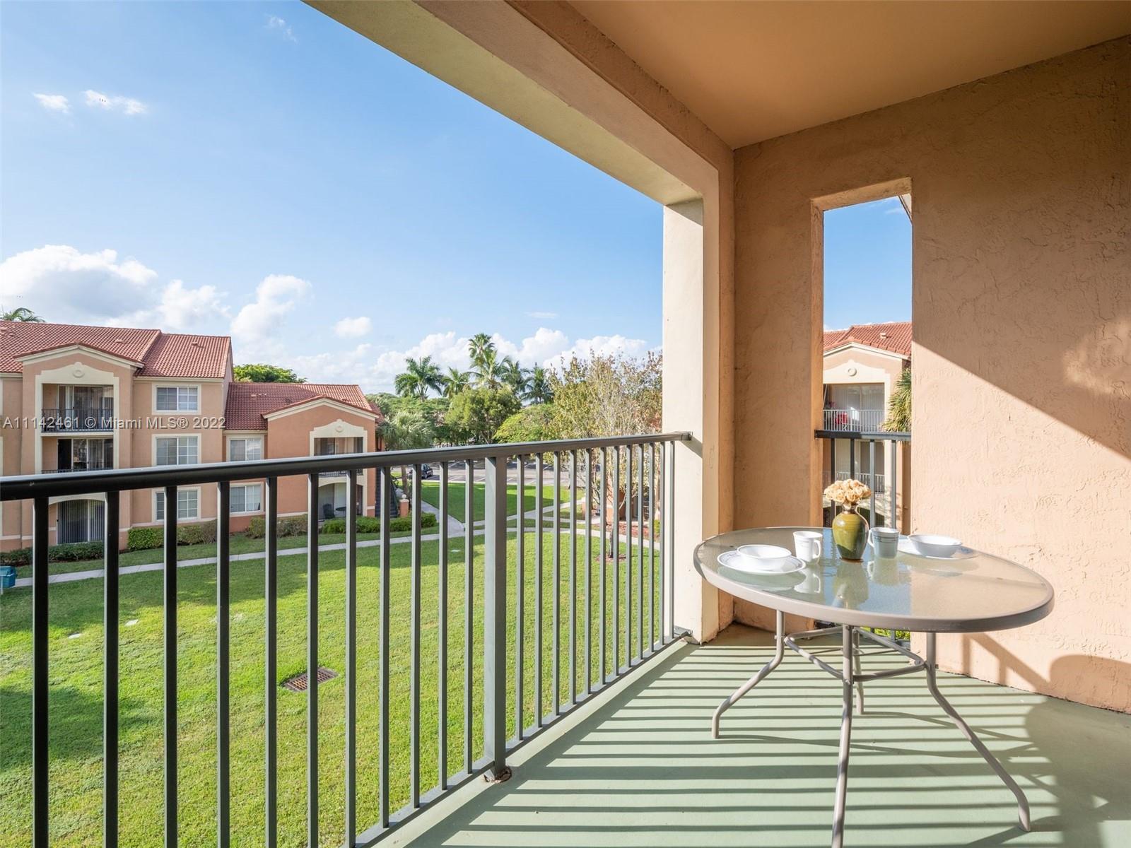 8030 North Nob Hill Road, Unit 306 Tamarac, FL 33321 - Photo 8 of 26 a balcony with wooden floor table and chairs