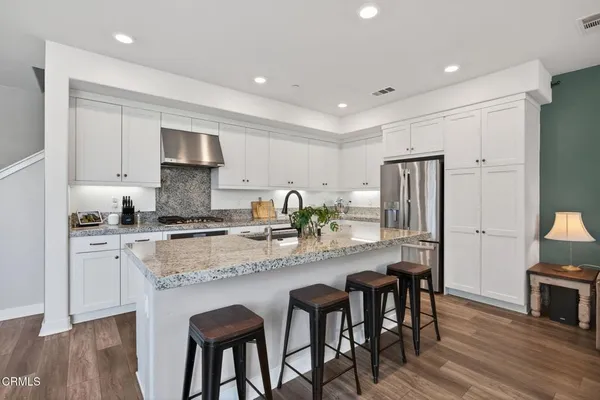 a kitchen with stainless steel appliances granite countertop a sink a stove and white cabinets